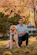 man in blue dress shirt sitting beside brown dog during daytime