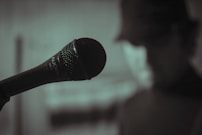 A close-up of a person recording a video with a microphone and soft lighting.
