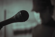Close-up of a microphone with blurred faces in the background during a video interview.