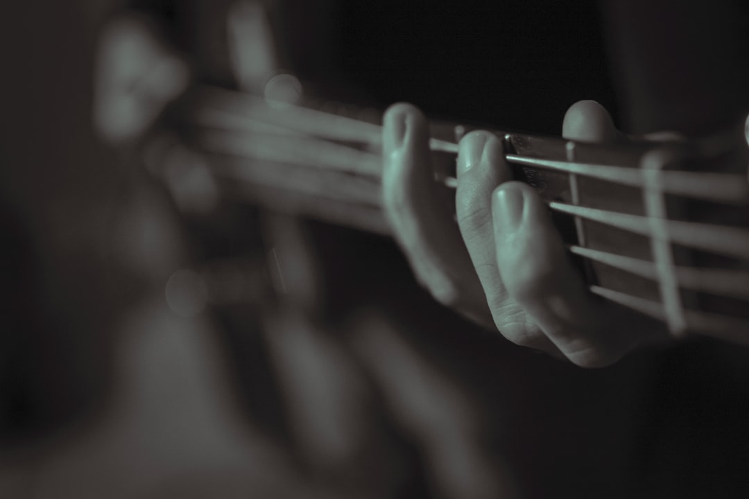 person playing guitar in grayscale photography