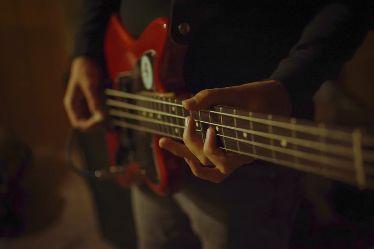 Fingers on the strings of a red electric bass