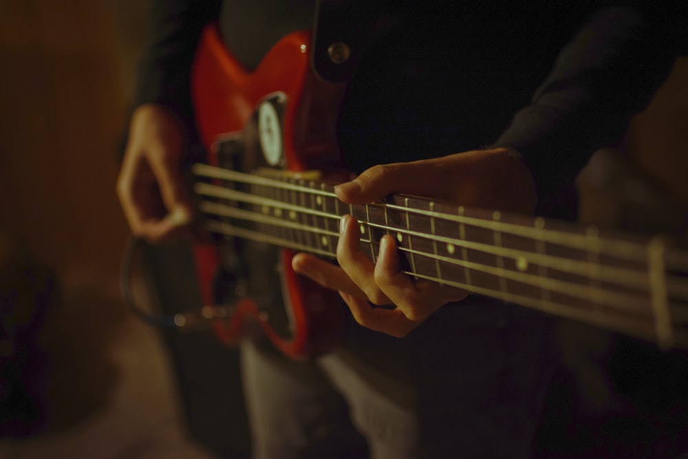 person playing red electric guitar