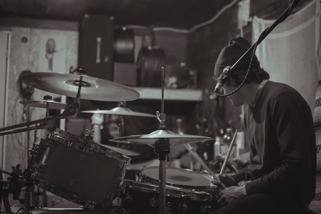 grayscale photo of man playing drum set