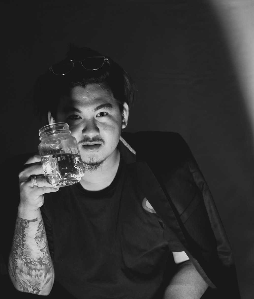 man in black suit holding clear glass jar