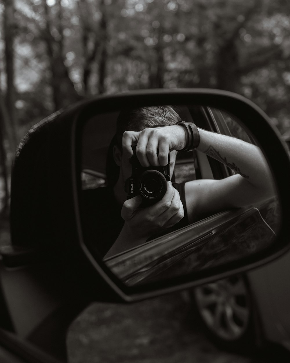 person taking photo of car side mirror