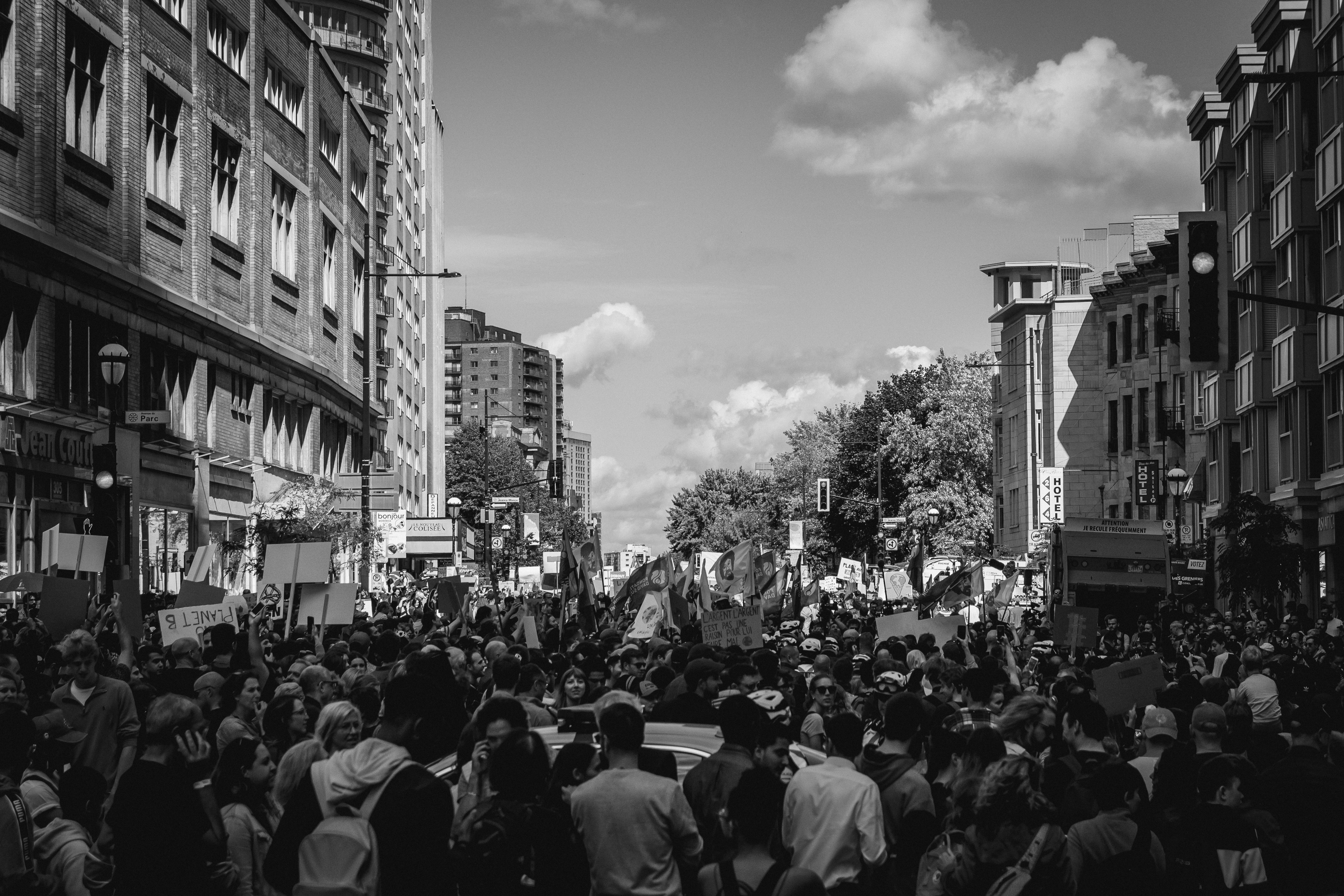 grayscale photo of people walking on street parade teams background