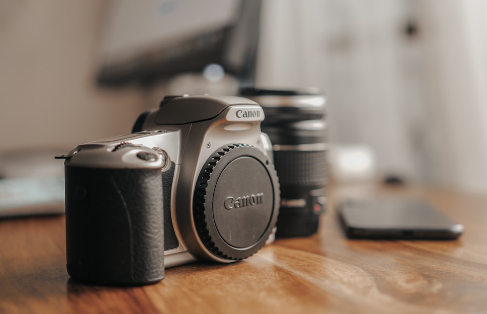 Schwarz-silberne Canon DSLR-Kamera auf braunem Holztisch