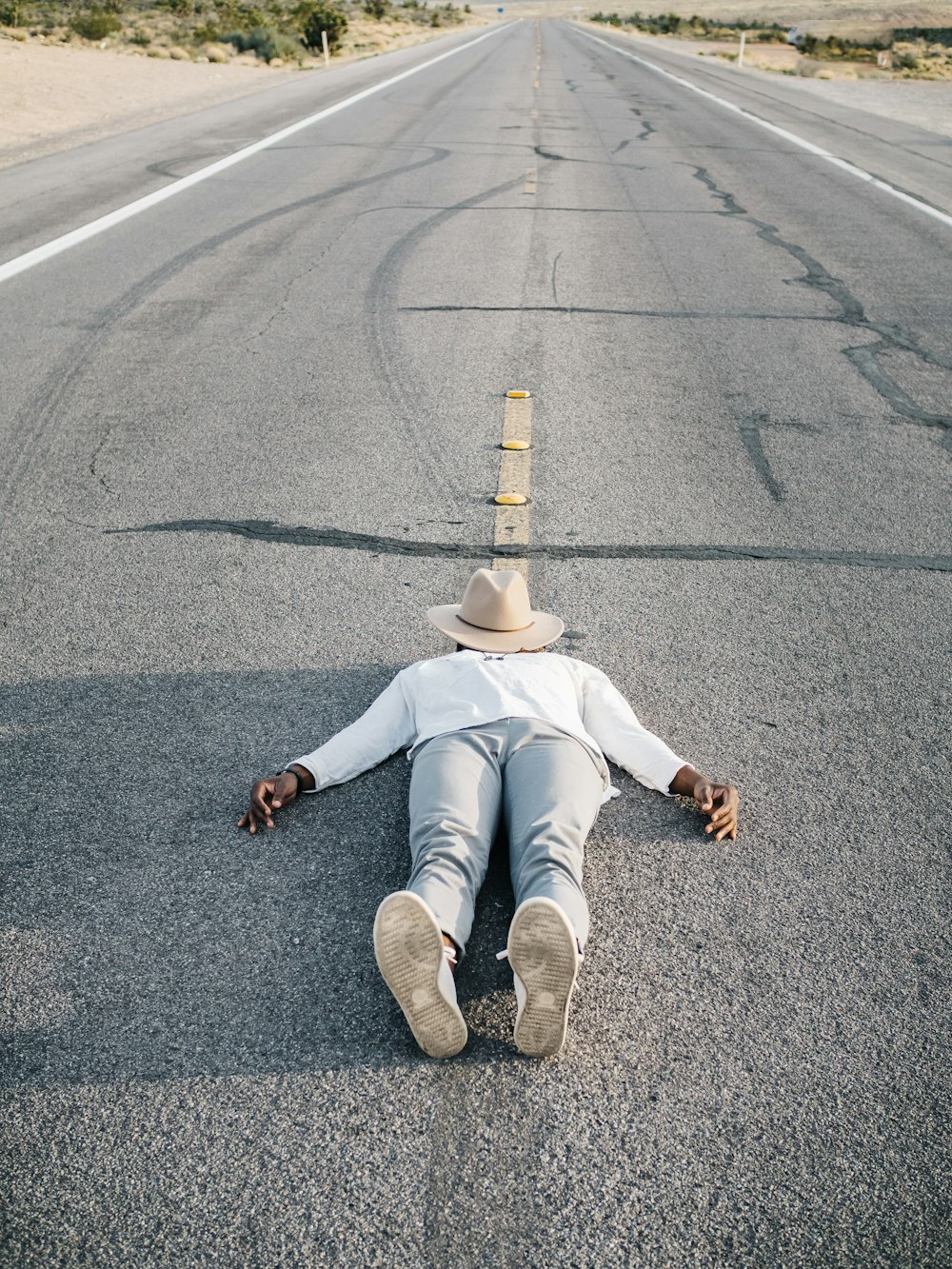 woman in white long sleeve shirt and blue denim jeans sitting on gray asphalt road during