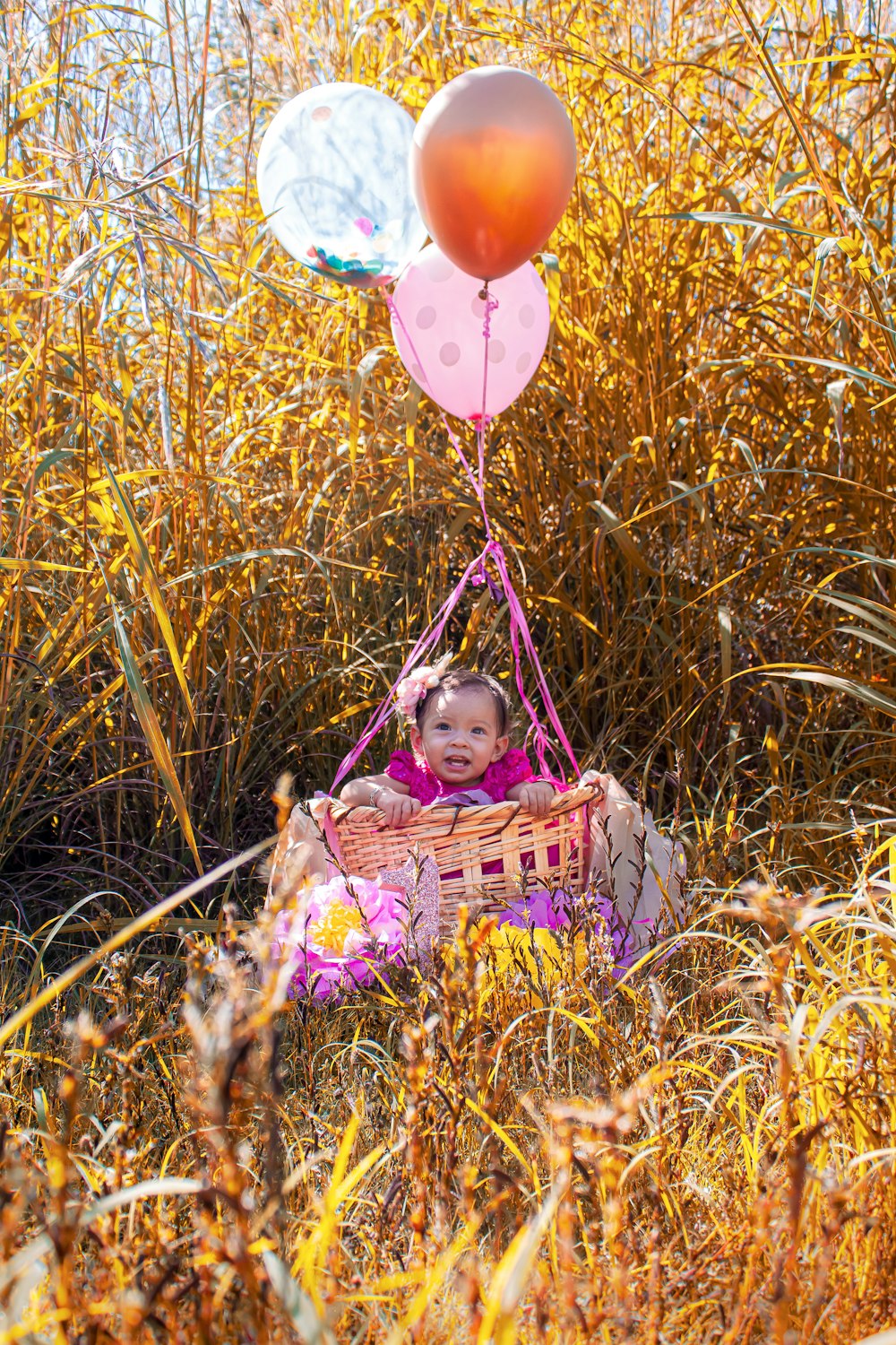 girl in pink dress holding balloons