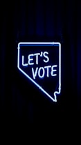 A neon sign in the shape of a state outline with the words 'LET'S VOTE' illuminated in bright blue against a dark background.