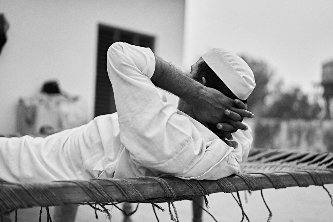  man in white long sleeve shirt sitting on chair bedstead bunk cot