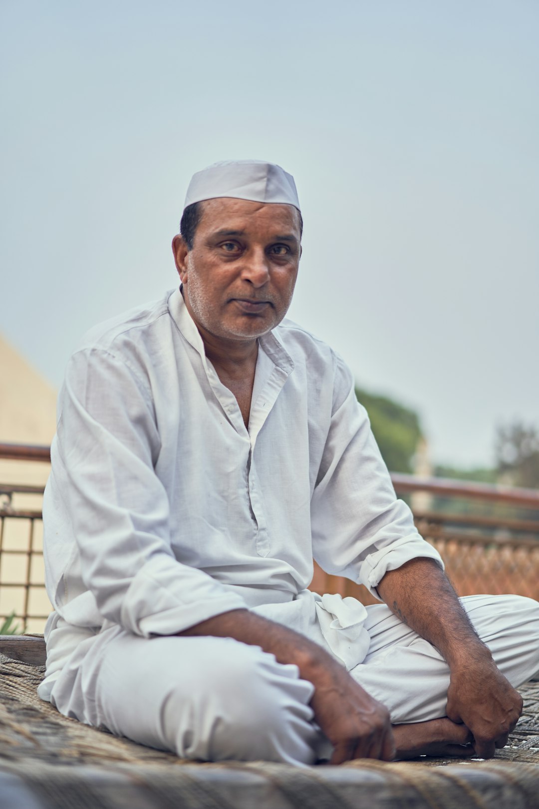 man in white thobe sitting on brown wooden bench during daytime