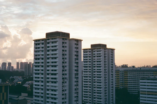 High-rise residential buildings with modern architecture in highlighted city neighborhoods during sunset.