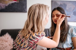 woman in blue and red shirt applying makeup