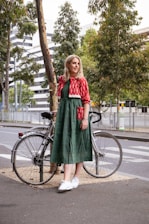 woman in red and green dress standing on road bike during daytime