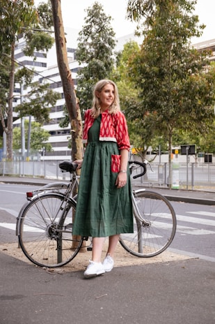 woman in red and green dress standing on road bike during daytime