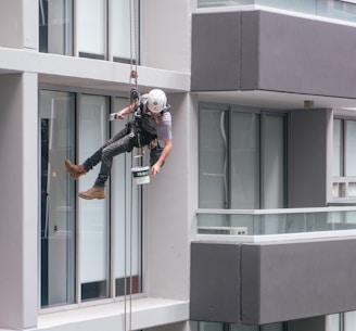 man in black jacket and black pants jumping on window during daytime