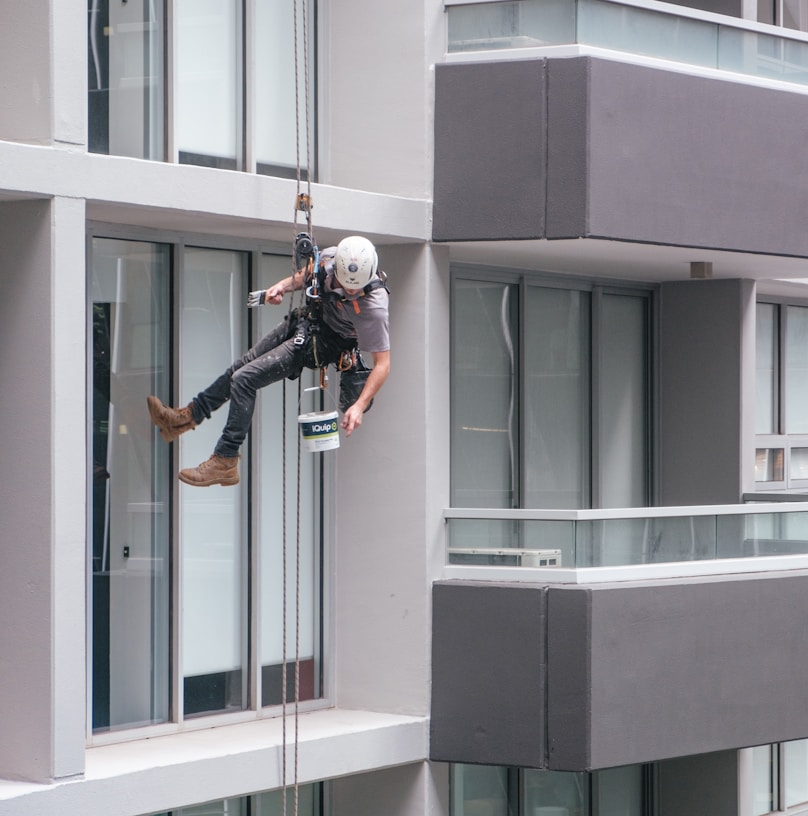 man in black jacket and black pants jumping on window during daytime