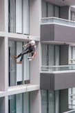 man in black jacket and black pants jumping on window during daytime