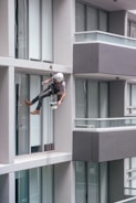 man in black jacket and black pants jumping on window during daytime