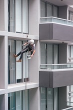 man in black jacket and black pants jumping on window during daytime