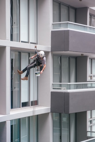 man in black jacket and black pants jumping on window during daytime