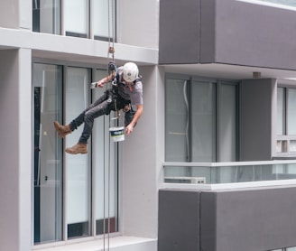 man in black jacket and black pants jumping on window during daytime