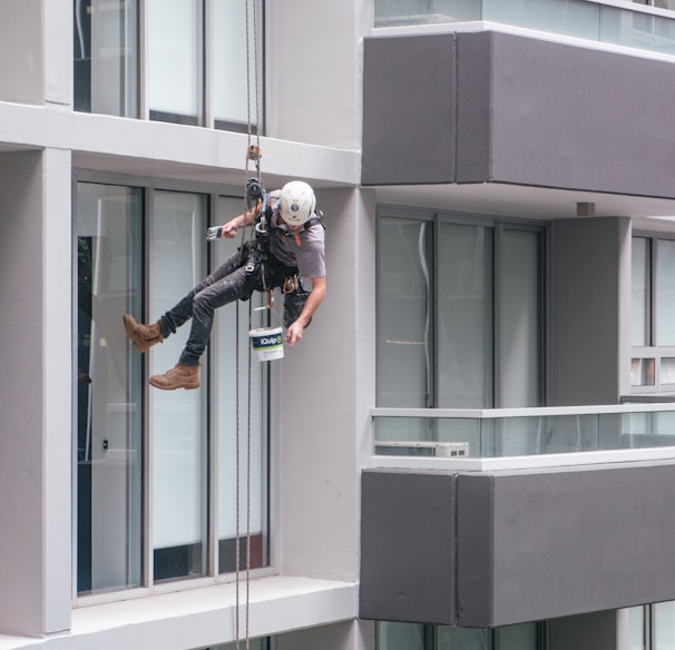 man in black jacket and black pants jumping on window during daytime