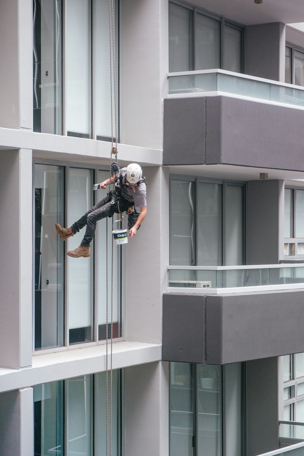 man in black jacket and black pants jumping on window during daytime