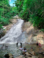 The cascading Limon Waterfalls sparkling under the sun, with visitors enjoying a refreshing swim.