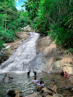 The cascading Limon Waterfalls sparkling under the sun, with visitors enjoying a refreshing swim.