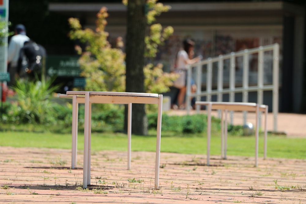 2 women standing on brown wooden bench during daytime