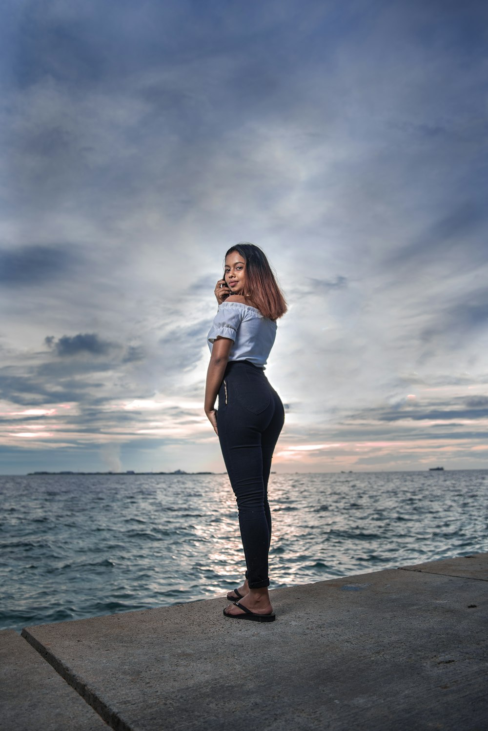 woman in white shirt and black pants standing on beach shore during daytime