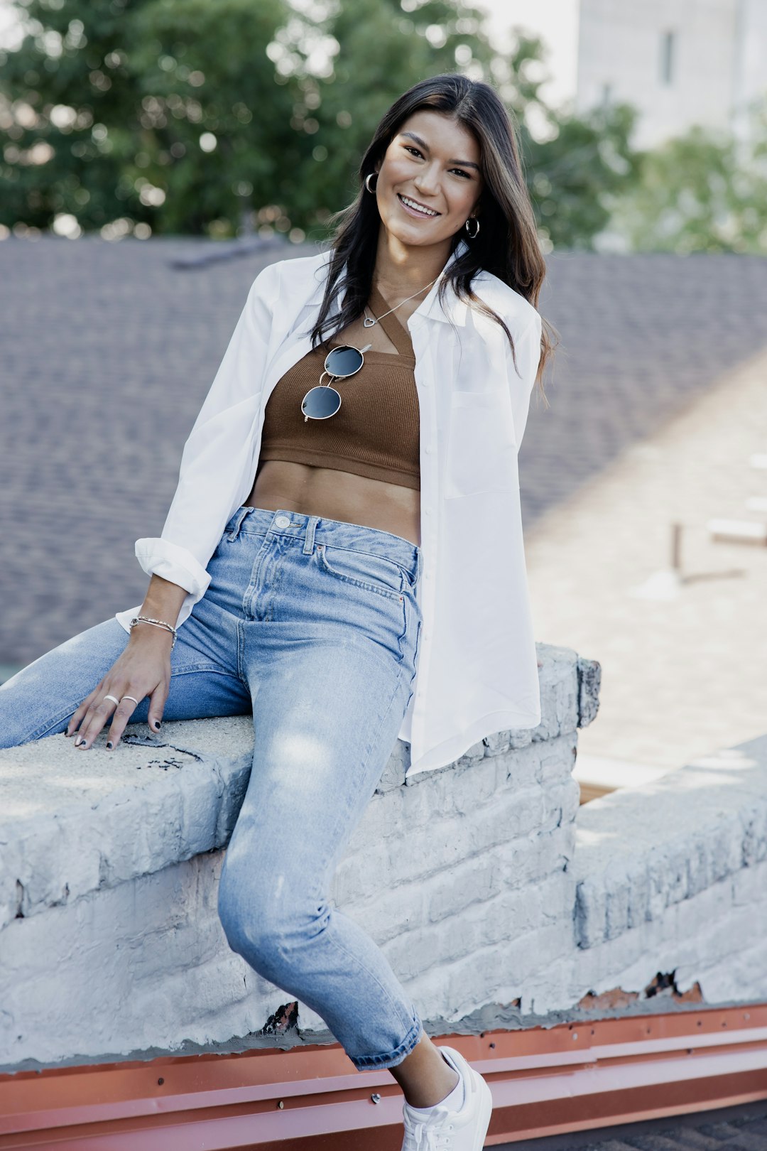 woman in white long sleeve shirt and blue denim jeans sitting on gray concrete bench during
