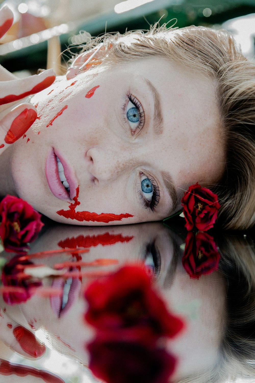 mulher com pétalas de flores vermelhas e brancas em seu rosto