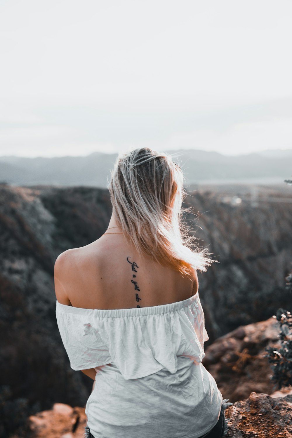 woman in white off shoulder dress standing on brown rock formation during daytime