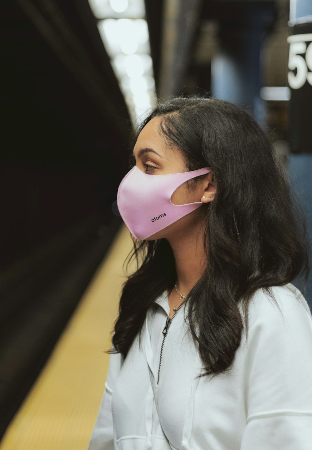 Frau im weißen Kragenhemd mit rosa Maske