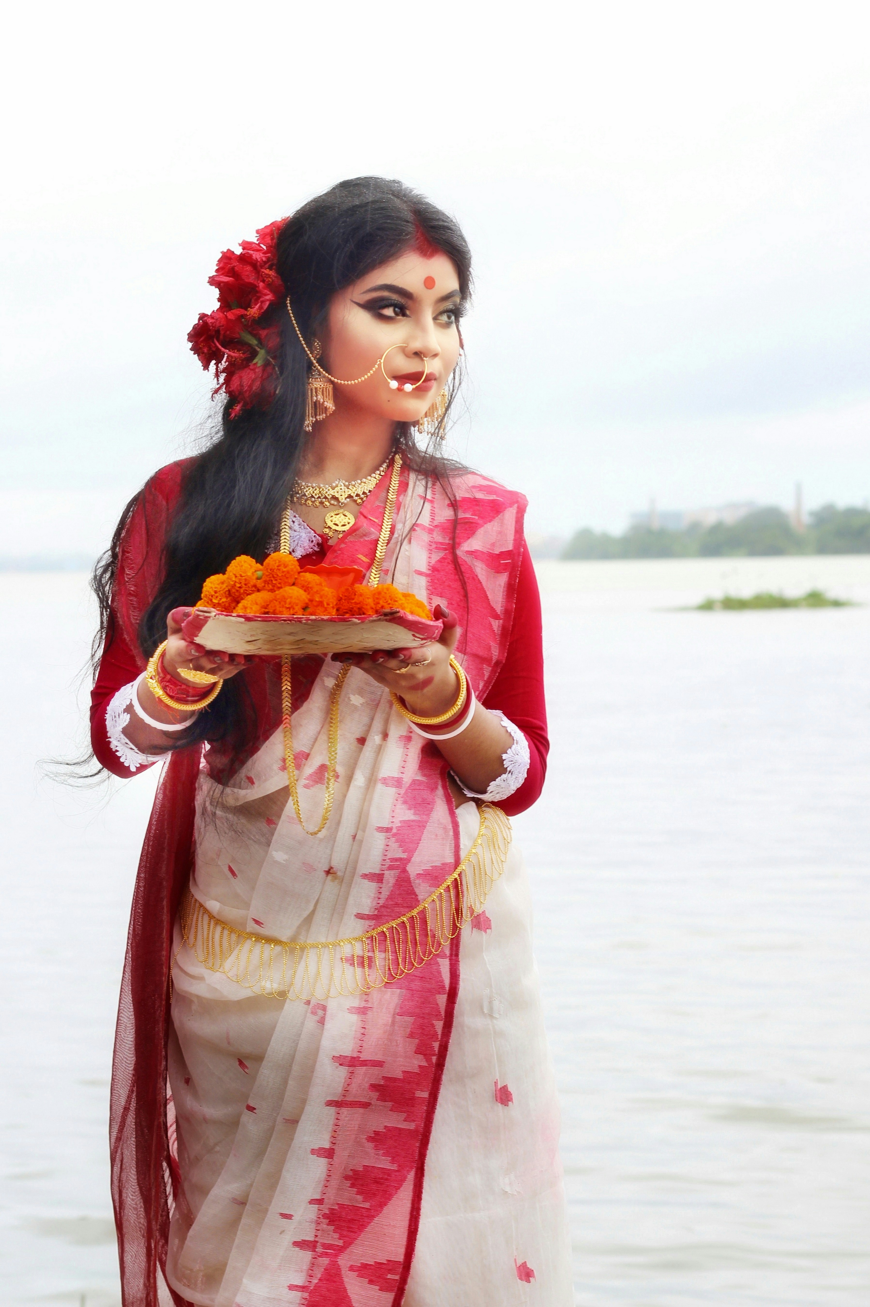Wanita berpakaian merah dan putih memegang piring dengan makanan