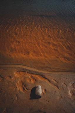 A crystal-clear bottle of Zamzam water glowing softly against a backdrop of golden desert sands at sunset.