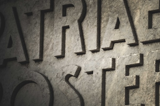 Large, carved stone letters are prominently displayed with a textured surface. The lighting casts shadows, creating depth and enhancing the rugged appearance of the stone.
