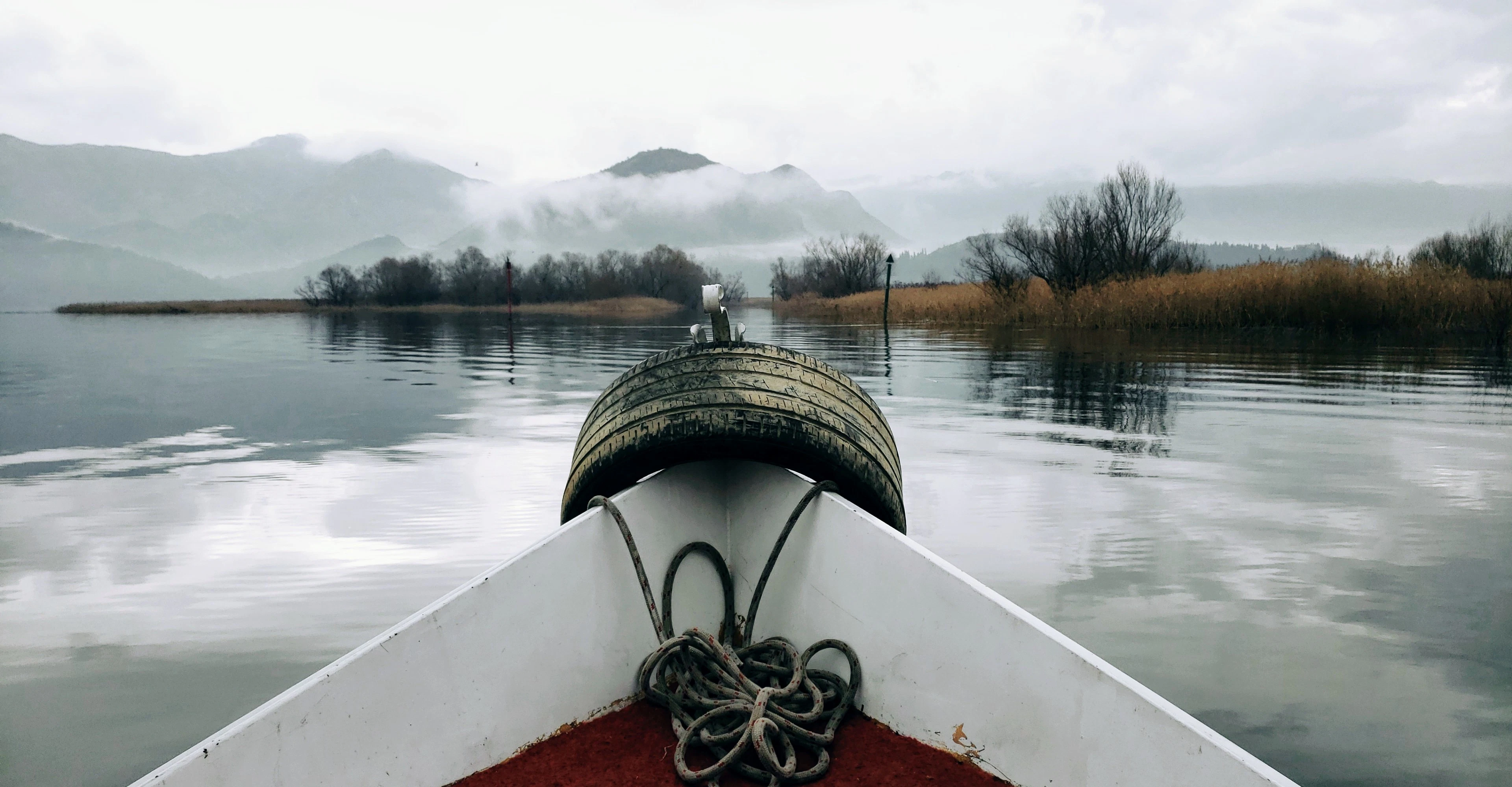 The bow of a boat on still, misty Lake Skadar