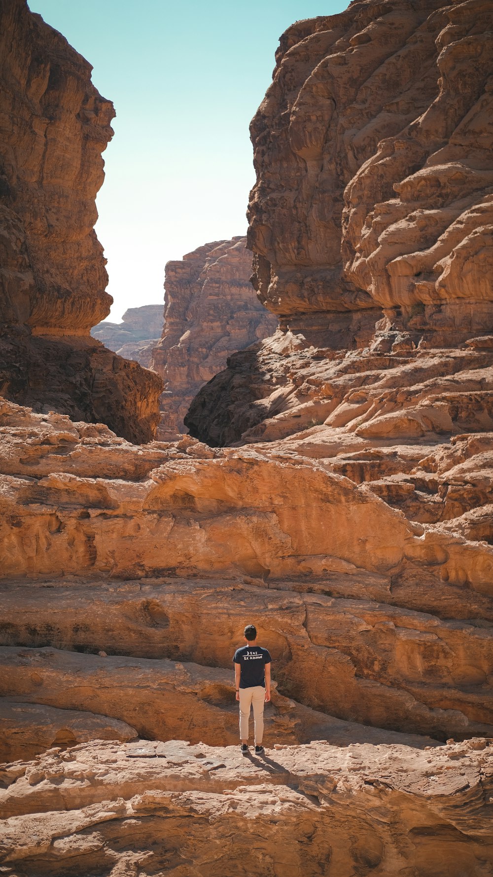 man in black jacket standing on brown rock formation during daytime