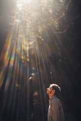 A man standing strong and hopeful in a sunlit forest, symbolizing spiritual freedom and renewal.