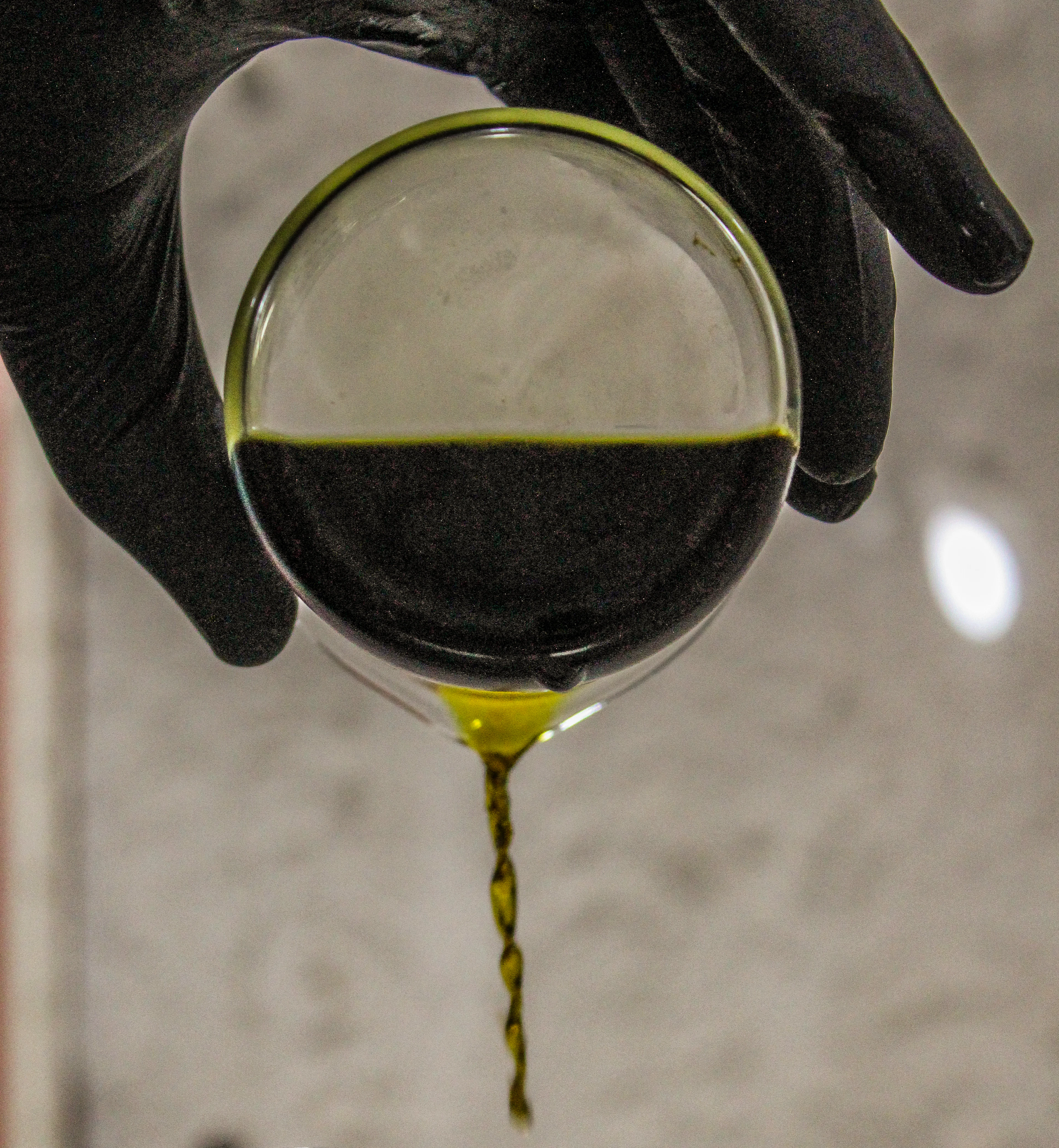 A gloved hand pouring a thread of golden essence
