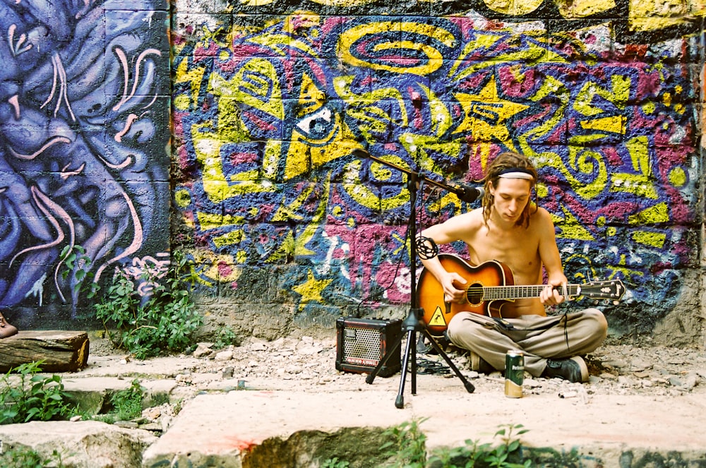 topless man sitting on chair near graffiti wall during daytime