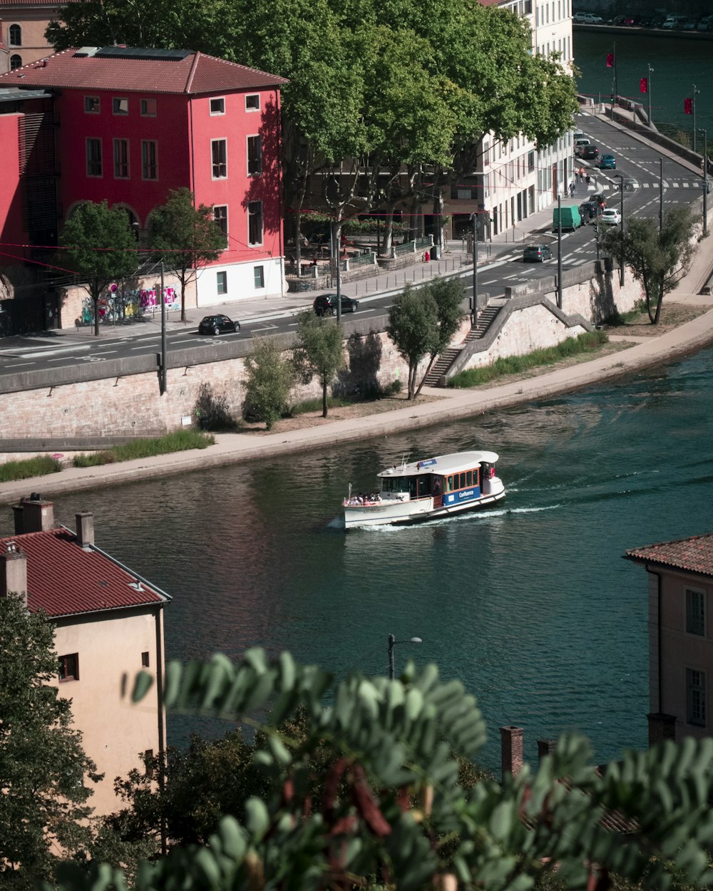 white and red boat on water near red concrete building during daytime