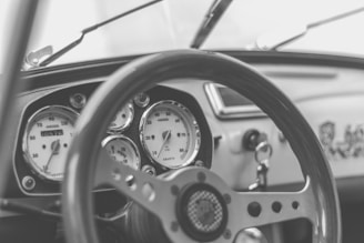 A close-up shot of a classic car dashboard with vintage gauges and a leather steering wheel.