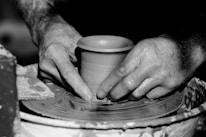 Close-up of hands crafting black clay pottery with rich textures.