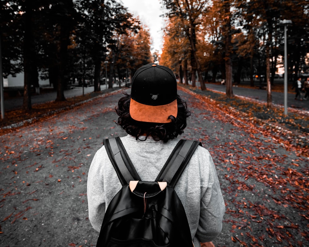 man in gray jacket wearing black backpack walking on road during daytime