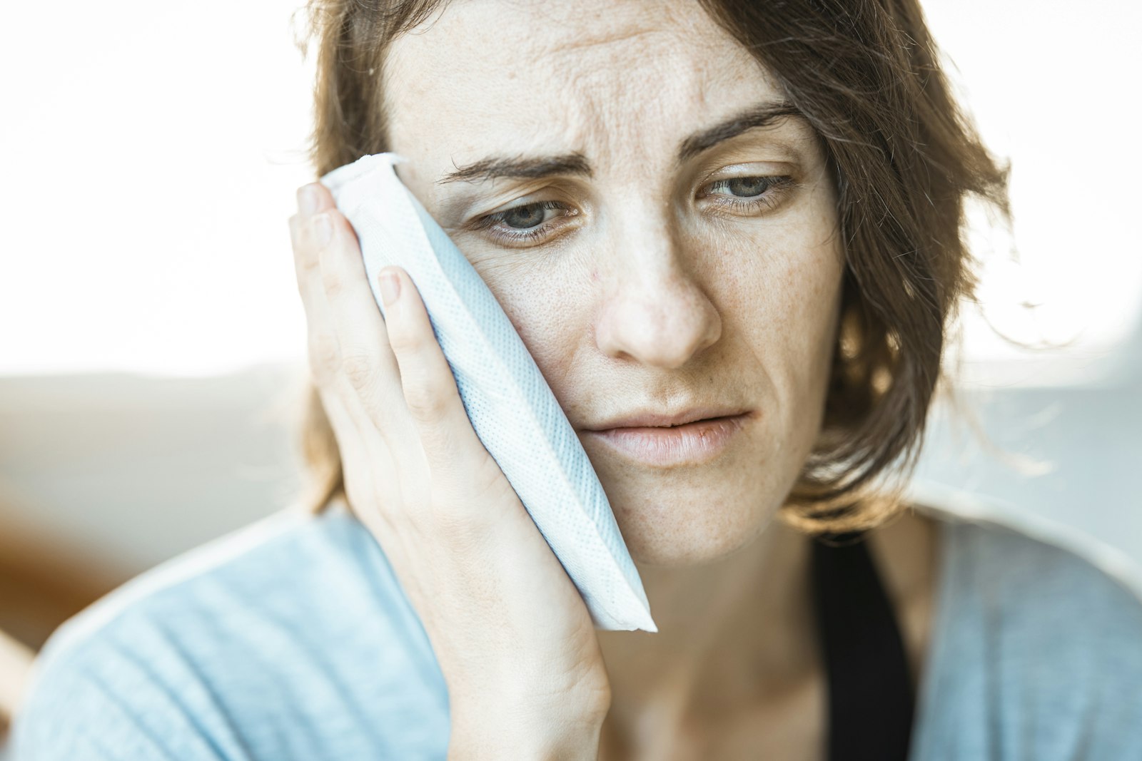 Person holding cold compress to jaw to ease cracked tooth pain in Sydney